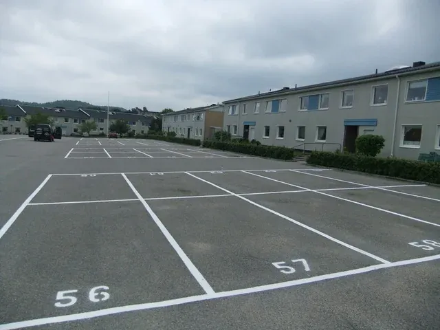 Numrerade parkeringsrutor framför ett flerbostadshus